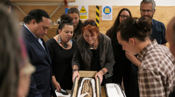 Group of people looking at a piece of taonga tūturu at the Ngāi Tahu Repatriation Ceremony in March 2023