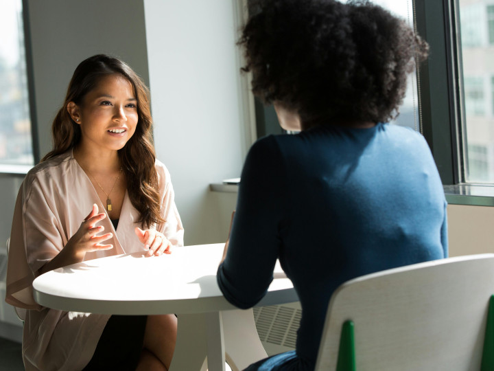 2 people sitting at a table and having a conversation