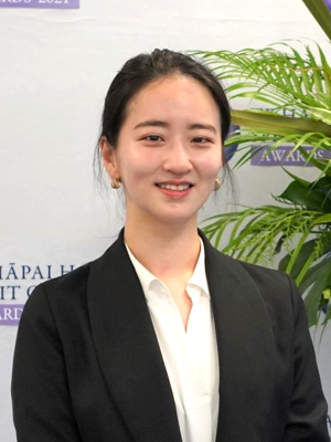 April Kwak standing in front of an awards banner looking at the camera and smiling