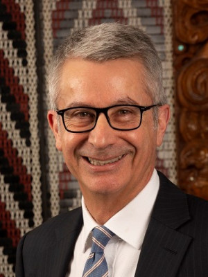 Bede Corry standing in front of a tukutuku panel looking at the camera and smiling