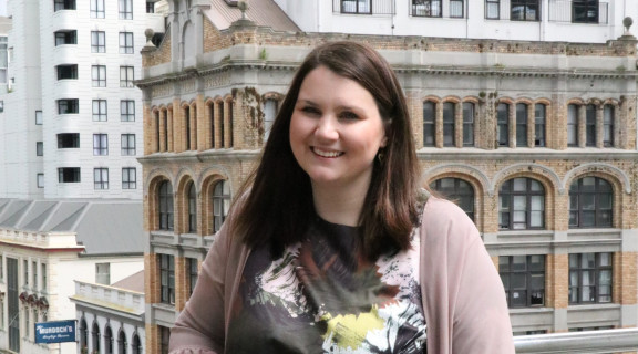 Cat Simpson standing in front of CBD buildings and smiling at the camera