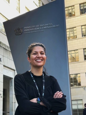 Chetna Pancha standing in front of the MBIE office looking at the camera and smiling