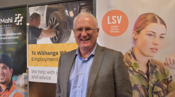 Craig Churchill standing in front of a careers banner looking at the camera and smiling