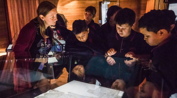 Group of school children looking at a display cabinet at the He Tohu exhibition
