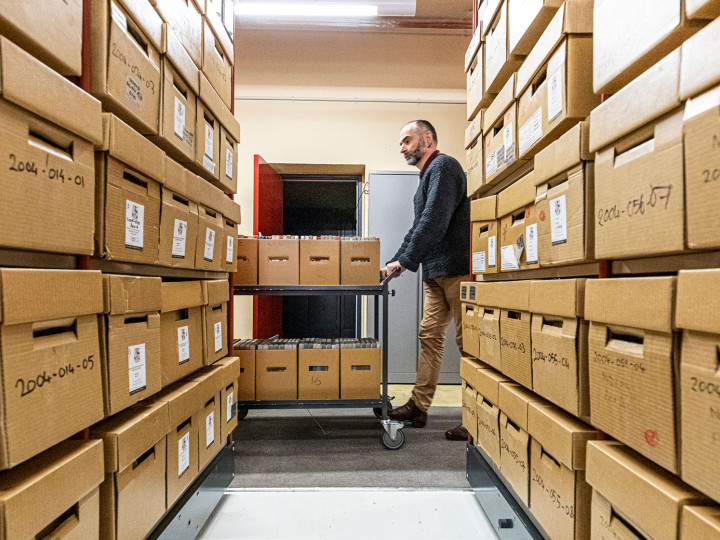 Department of Internal Affairs curator wheeling a trolley of recordings in a storage room