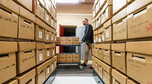 Department of Internal Affairs curator wheeling a trolley of recordings in a storage room