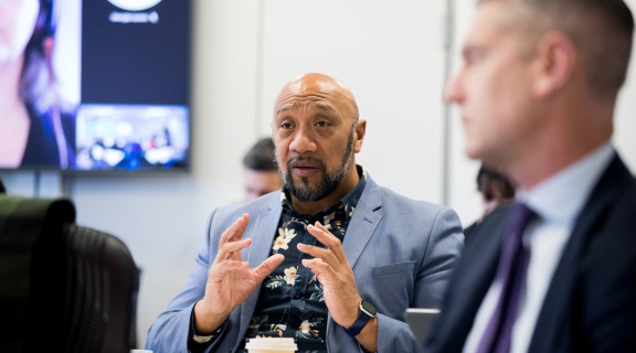Ezra Schuster talking with a group of people in a meeting room