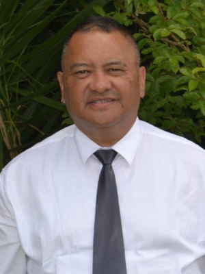 Geoff wearing a white shirt and grey tie looking at the camera and smiling