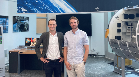 Isaac Hollis and Tim Searle surrounded by space equipment looking at the camera and smiling