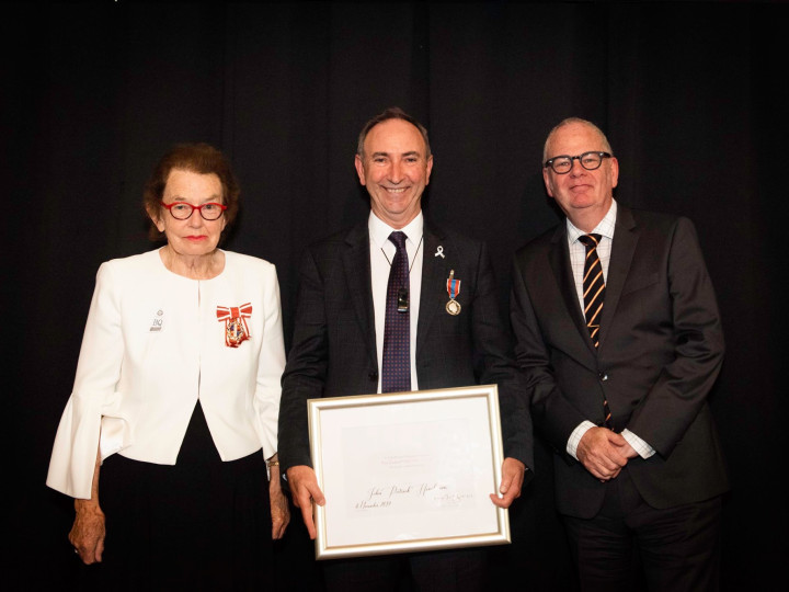 John Henderson standing between Dame Margaret Bazley and Peter Hughes holding his Public Service Award 