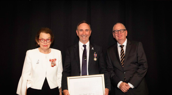 John Henderson standing between Dame Margaret Bazley and Peter Hughes holding his Public Service Award 