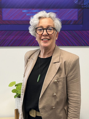 Karen Bartlett wearing a brown blazer looking at the camera and smiling