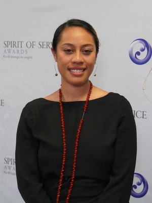Mary Soonaoso Tiumalu standing in front of awards banner and smiling at the camera