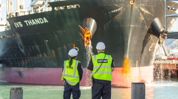 NZ Customs two Customs officers looking at boat coming into harbour captioned