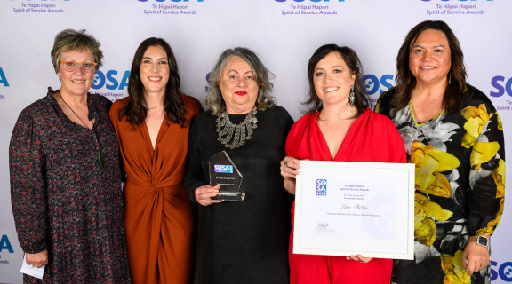 The Love Better campaign team standing in front of the SOSA banner smiling at the camera