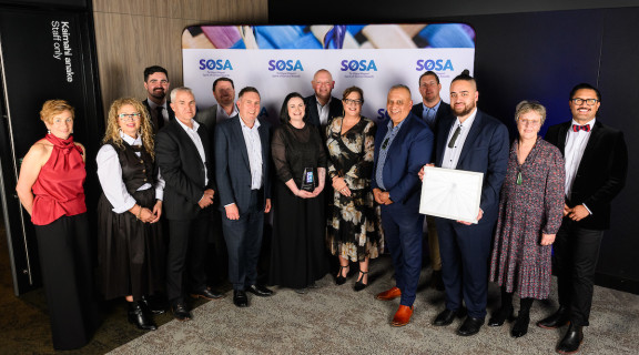 The DLIP team standing in front of the SOSA banner smiling at the camera