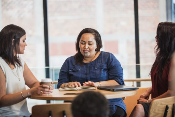 Three women sitting a table reading a document