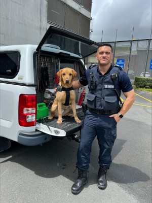 Tom Parima standing next to detector dog Sammy outside the prison gates