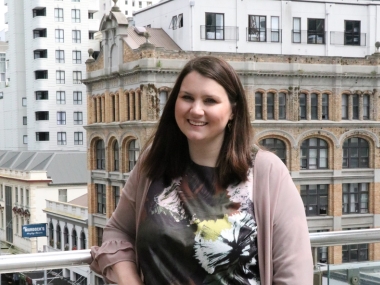 Cat Simpson standing in front of CBD buildings and smiling at the camera