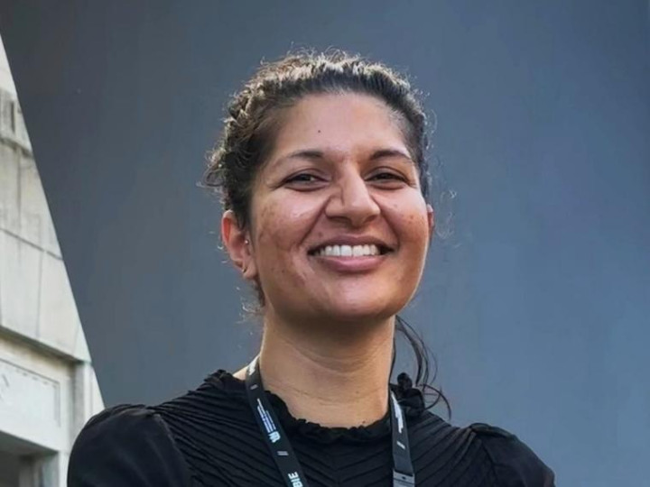 Chetna Pancha standing in front of the MBIE office looking at the camera and smiling
