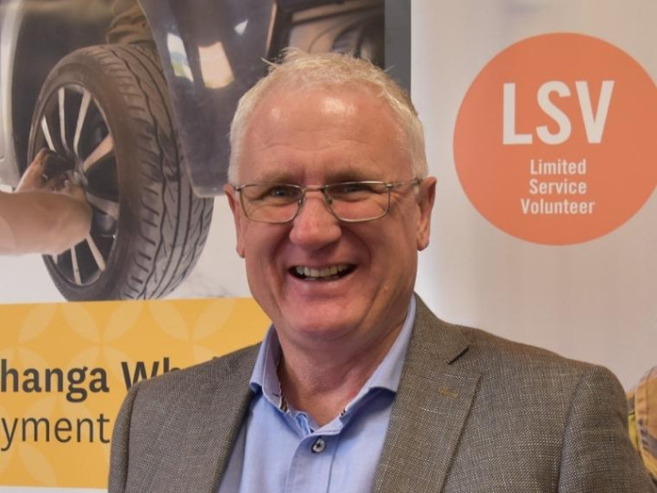 Craig Churchill standing in front of a careers banner looking at the camera and smiling