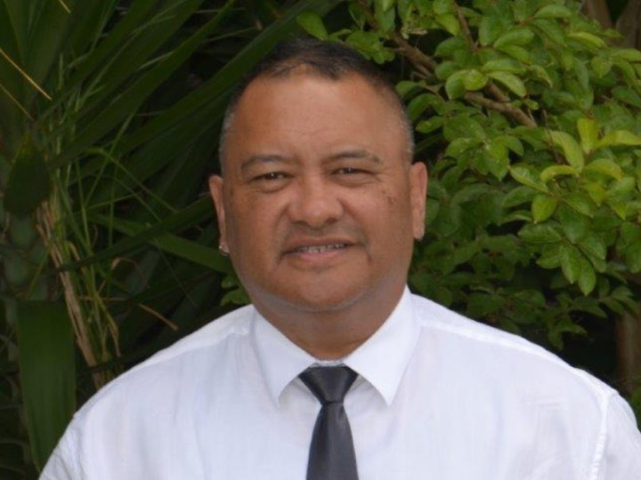 Geoff wearing a white shirt and grey tie looking at the camera and smiling