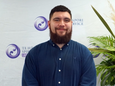 Jacob McGregor standing in front of awards banner and smiling at the camera