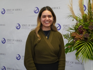 Kiriana Haze standing in front of awards banner and smiling at the camera