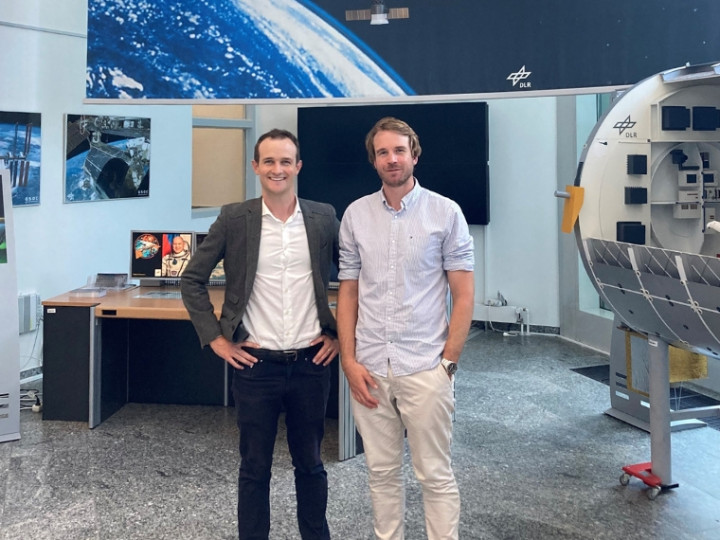 Isaac Hollis and Tim Searle surrounded by space equipment looking at the camera and smiling